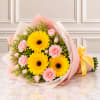 Bouquet of yellow gerbera daisies and pink carnations wrapped in pastel paper