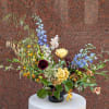 Mixed floral arrangement in a black vase with blue, yellow, and burgundy blooms