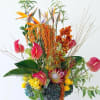 Tall tropical floral arrangement with orange birds of paradise and pink anthuriums in a vase
