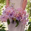 Bride holding a cascading bouquet of pink and lavender orchids