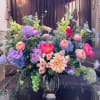 Large mixed bouquet in a metallic vase with pink, purple, and yellow blooms