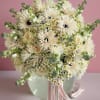 Creamy white bouquet with roses and daisy-like flowers in a pale vase