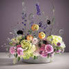Mixed floral arrangement in a white bowl with pink, yellow, and purple blooms