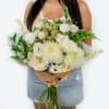Large bouquet of white flowers with green accents wrapped in brown paper