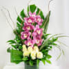 Pink orchids and white roses arranged in a tall green vase
