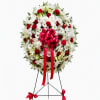 Standing floral wreath of white and red flowers with a pink ribbon bow