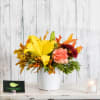 Yellow lily and carnations in a white vase with autumn leaves
