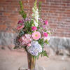 Tall pastel bouquet in a clear glass vase on a stool