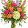 Colorful mixed bouquet in a clear glass vase with roses, hydrangea, and tall blooms