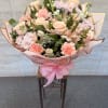Large bouquet of pink and peach flowers wrapped in pink paper with a ribbon