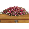 Pink and red floral casket spray on a wooden casket