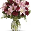 Arrangement of pink lilies and red roses in a clear glass vase