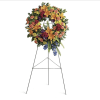 Large floral wreath on a standing easel with mixed orange, pink, purple, and yellow flowers