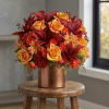 Red and orange floral arrangement in a copper vase