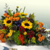 Colorful floral arrangement with sunflowers and orange roses in a low container