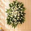White floral standing spray on an easel with palm leaves