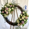 Large floral wreath with white, pink, and blue flowers on a wooden stand