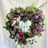 Heart-shaped floral wreath with pink and purple flowers on a metal stand