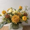 Mixed yellow and cream flowers arranged in a glass vase