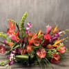 Tropical floral arrangement with orange heliconia, red anthuriums, and purple orchids