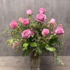 Pink roses arranged in a clear glass vase with small pink filler flowers.