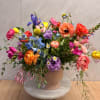 Colorful mixed flower arrangement in a blush ceramic vase on a marble stand