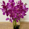 clear glass vase with a black stones and 5 orchids.
Orchids can be