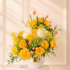 Yellow roses and white blooms in a white vase with pink tulips