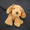 Plush tan dog toy sitting on a dark fabric background