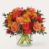Orange and red roses with yellow daisies in a clear glass vase