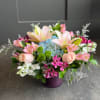Mixed bouquet in a purple vase with pink lilies, roses, and blue hydrangea