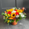 Colorful bouquet of sunflowers, roses, and white blooms in an orange vase
