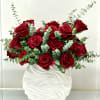 Arrangement of red roses and eucalyptus in a textured white ceramic vase