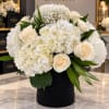 White hydrangea and cream rose arrangement in a black box