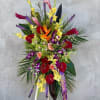 Tall tropical flower arrangement with orchids, anthuriums, and bright mixed blooms
