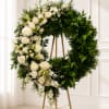 Large white and green floral wreath on a gold stand