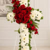 Standing floral cross with red roses and white daisies on an easel