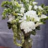 White flowers and green accents arranged in a clear glass vase
