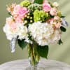 Pink and white roses with hydrangeas in a clear glass vase