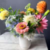 Mixed bouquet of colorful flowers in a white vase