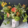 Mixed bouquet in a white vase with coral, white, and green blooms