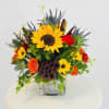 Bright mixed bouquet with sunflowers and orange roses in a glass vase