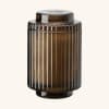 Amber ribbed glass jar with a black lid on a plain background