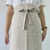 Person wearing a light beige apron tied at the waist