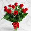 Red roses in a clear glass vase with baby's breath and a red ribbon