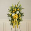 Yellow and white floral standing spray with a yellow ribbon on an easel