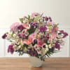 Pink lilies and purple mixed flowers arranged in a white vase