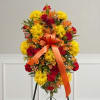 Bright floral standing spray with yellow and red flowers and an orange ribbon