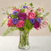 Mixed pink and purple flowers arranged in a clear glass vase