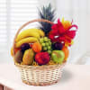 Fruit basket with bananas, grapes, apples, and a pineapple